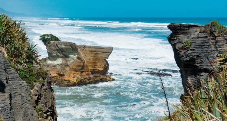 Coastal rock formations with ocean waves crashing against them.