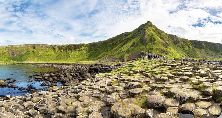 Vue panoramique de la Chaussée des Géants avec des touristes qui explorent.