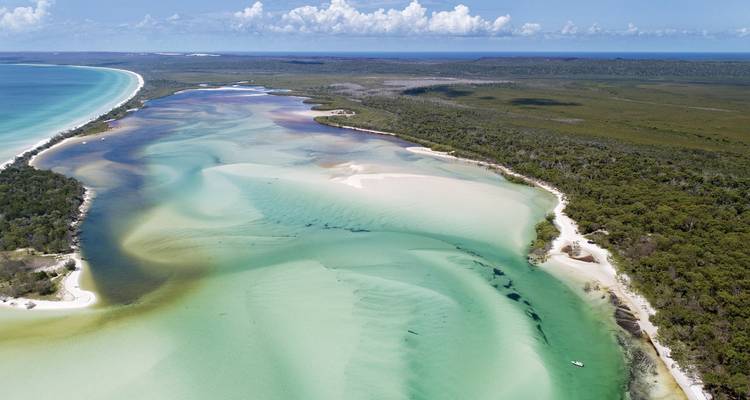 Luftaufnahme einer Küstenlandschaft mit klarem türkisfarbenem Wasser und Sandbänken.