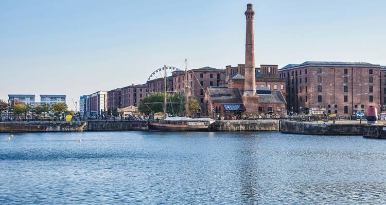 Harbor view with historic buildings and a tall chimney.