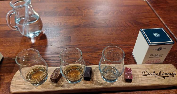 Tabla de madera con vasos de whisky y chocolates.