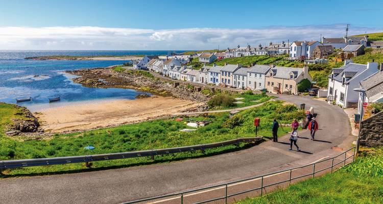 Pintoresco pueblo costero con gente caminando por un camino junto al mar.