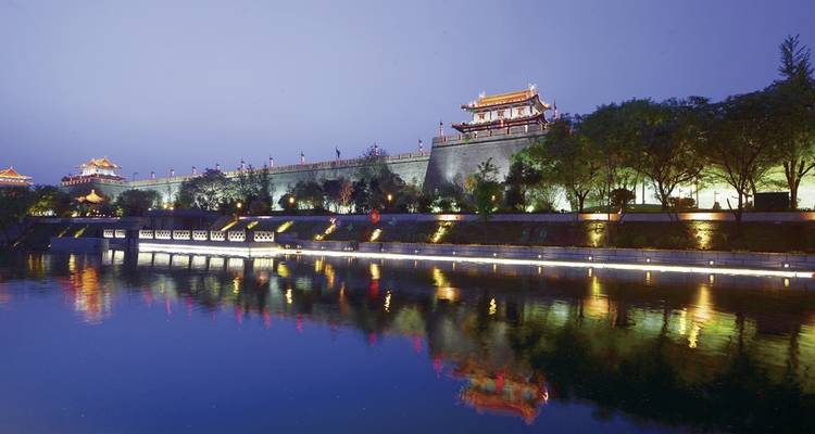 Stadtmauer bei Nacht mit Spiegelungen auf dem Wasser.