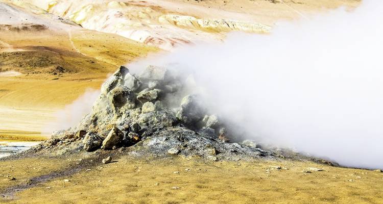 Fumarola geotérmica emitiendo vapor en un paisaje árido.