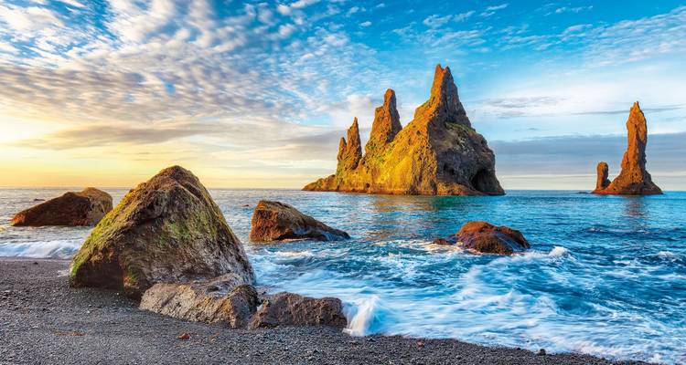 Felsformationen am Strand Reynisfjara mit dramatischer Beleuchtung.