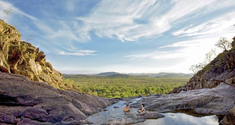 Menschen genießen einen natürlichen Pool mit Blick auf ein Tal.