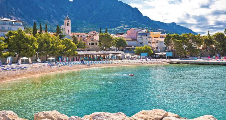 A beachside village with mountains in the background.