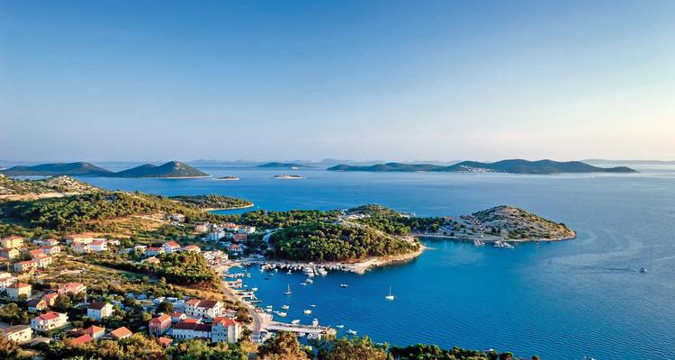 Kustplaats met haven en boten, omringd door eilanden.