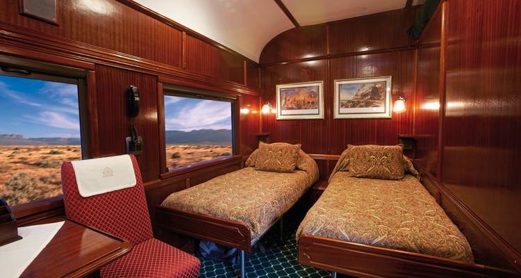 Luxueuze interieur van een treincoupé met bedden en ramen.