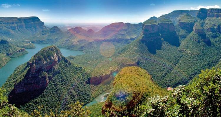 Ein umfassender Blick auf die grüne Blyde River Canyon offenbart imposante Tafelberge und einen gewundenen Fluss weit darunter.