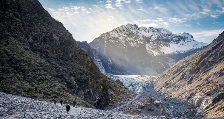 Hikers walking towards a snowy mountain.