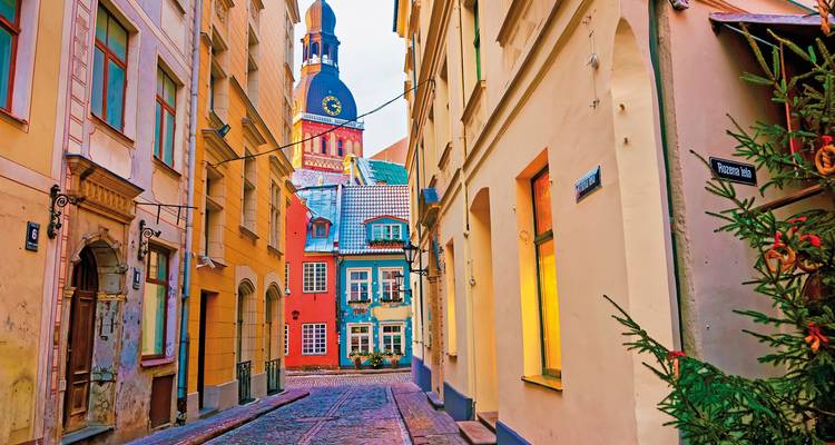 Bunte Kopfsteinpflasterstraße mit einem Kirchturm im Hintergrund.