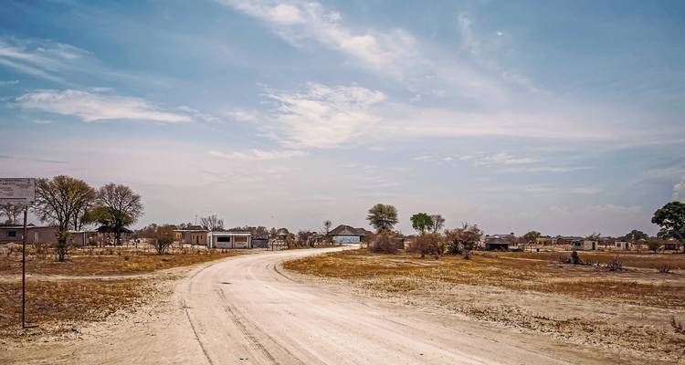Chemin de terre menant à un petit hameau rural.