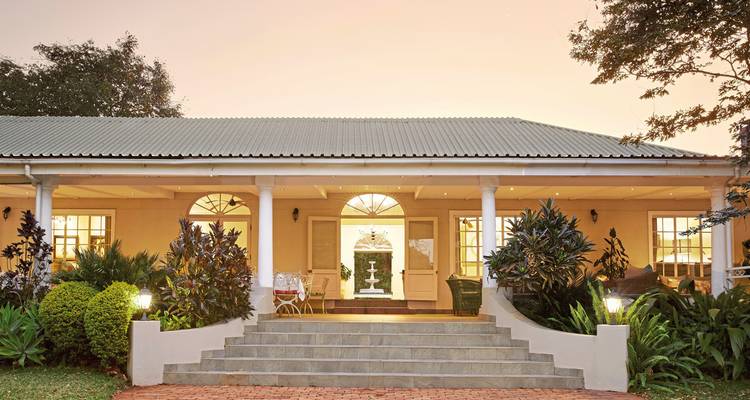 Een charmant huis uit het koloniale tijdperk met brede trappen en decoratieve planten.