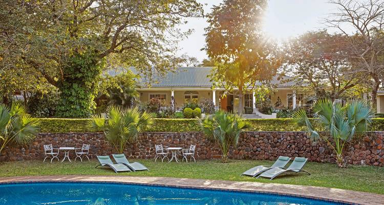 Een ruime villa omringd door weelderige tuinen met een zwembad.