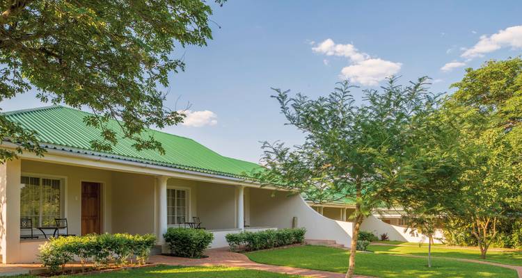 Een charmant pension met een groen dak en verzorgde gazons.