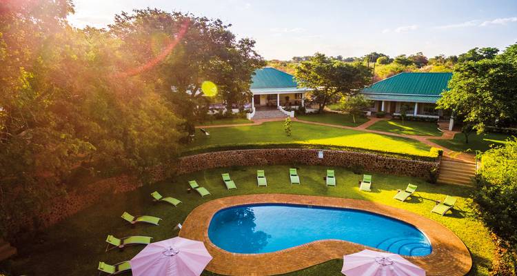 Luchtfoto van een villa met een zwembad en weelderige omliggende tuinen.