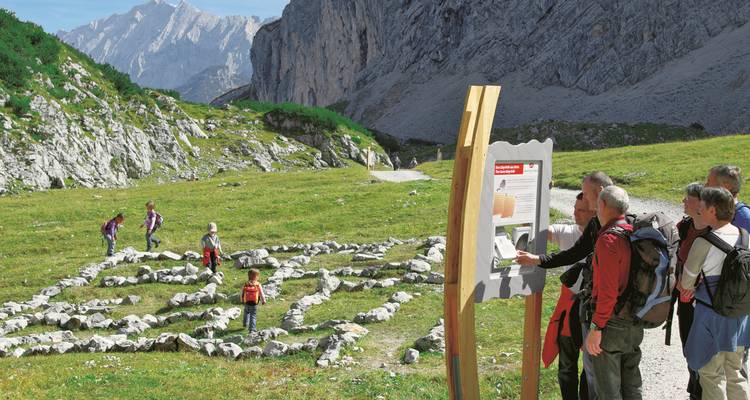 Menschen wandern und betrachten eine große, felsige Landschaft.