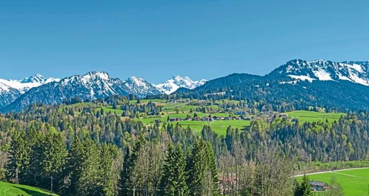 Malerische Aussicht auf ein Dorf mit Bergen und grünen Feldern.
