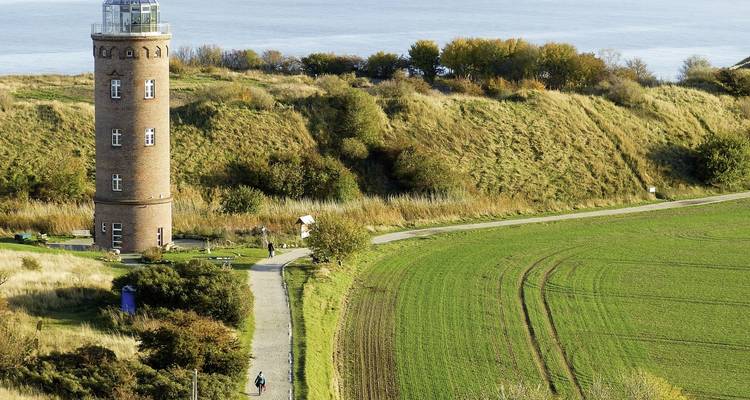 Un faro histórico rodeado de vegetación y un paisaje costero.