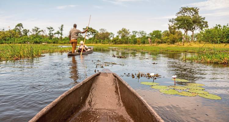 Canoë naviguant dans une voie navigable bordée de roseaux.