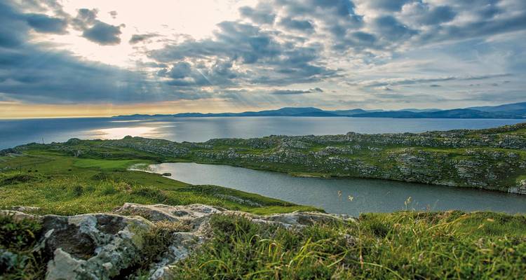 Un littoral serein avec des paysages rocheux sous des ciels dramatiques.