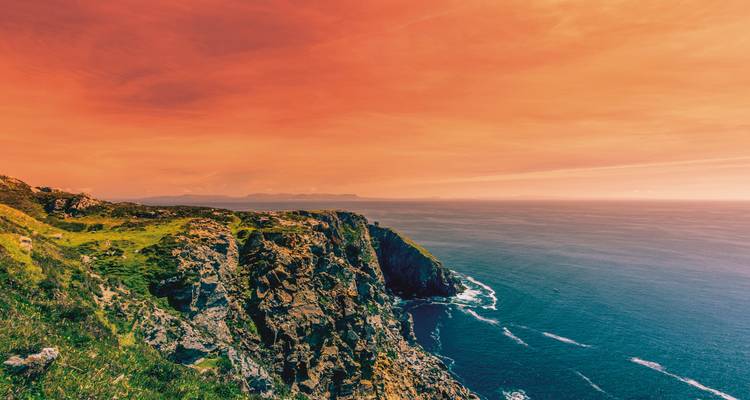 Falaise avec un ciel orange dramatique en arrière-plan.