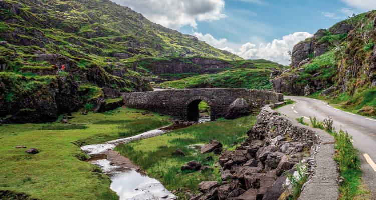 Pont de pierre au-dessus d'un petit ruisseau dans un paysage luxuriant.