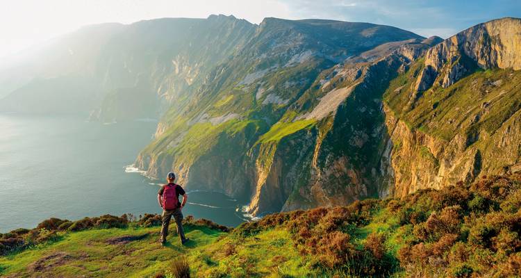 Personne faisant de la randonnée sur une falaise avec vue sur l'océan.