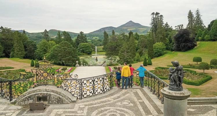 A family enjoying the view of a mountainous landscape from a garden terrace.