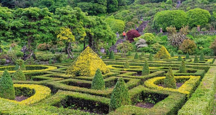 Decorative garden with hedges and steps, people visible in the background.