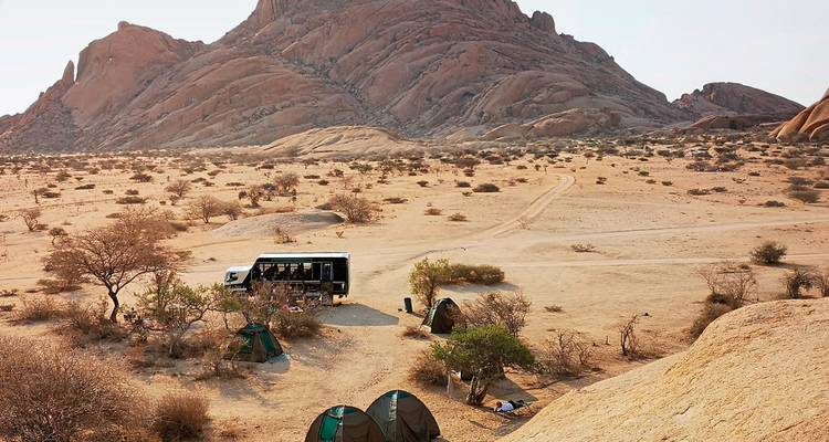 A desert campsite with a mountain and tour bus.