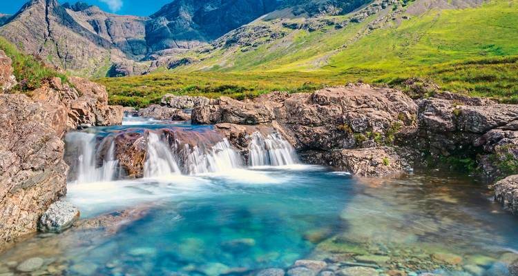 Un ruisseau bleu clair qui coule sur des rochers dans une région montagneuse.