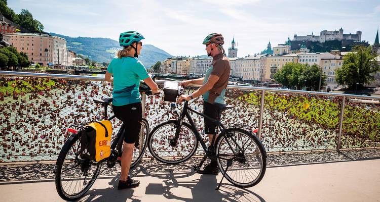 Two cyclists overlooking a cityscape with historical architecture.