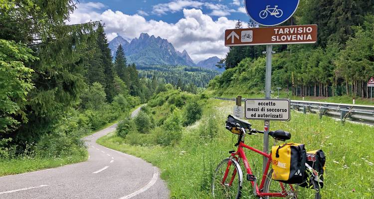 Bicycle next to road signs with a view of mountains.