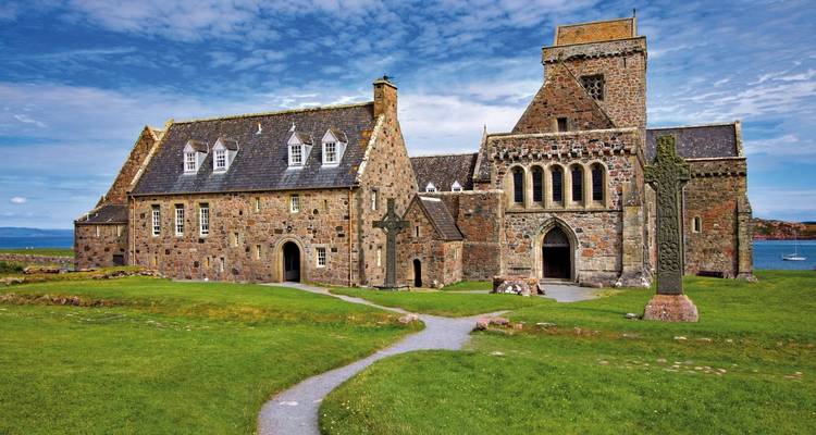 Steinerne Iona-Abtei mit keltischem Kreuz auf üppig grünen Grundstücken am Meer gelegen.