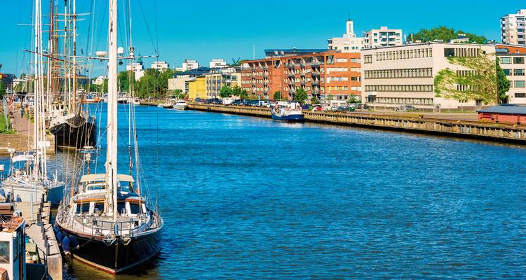Een kanaal met boten en moderne gebouwen op een zonnige dag.