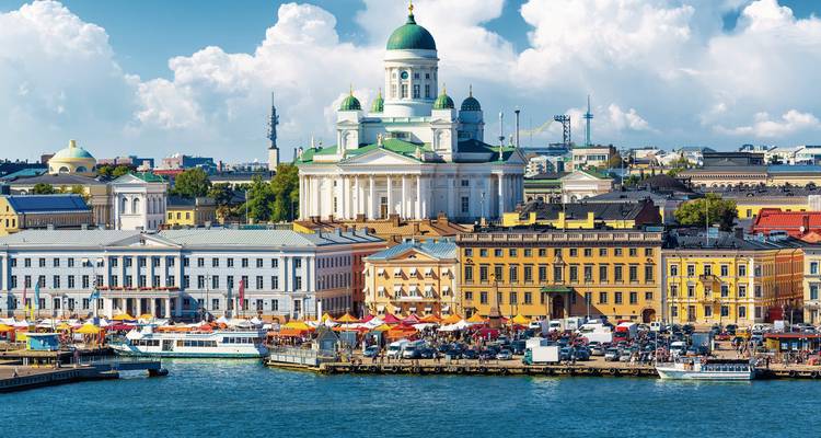 Een zicht op de Kathedraal van Helsinki met kleurrijke markttenten bij het water.