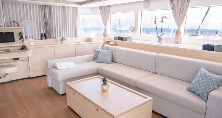 Moderne jachtlounge met licht zitmeubel, zeezicht door grote ramen en houten vloeren