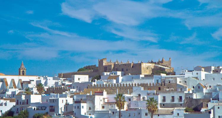 Weiß getünchte Häuser und eine Bergfestung unter einem leuchtend blauen andalusischen Himmel in Vejer de la Frontera.