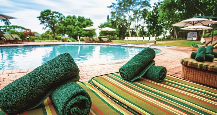 Schwimmbad mit Liegestühlen und Handtüchern in einem üppigen Garten.