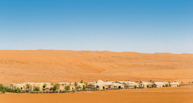 Woestijnresort met gebouwen in zandige omgeving.