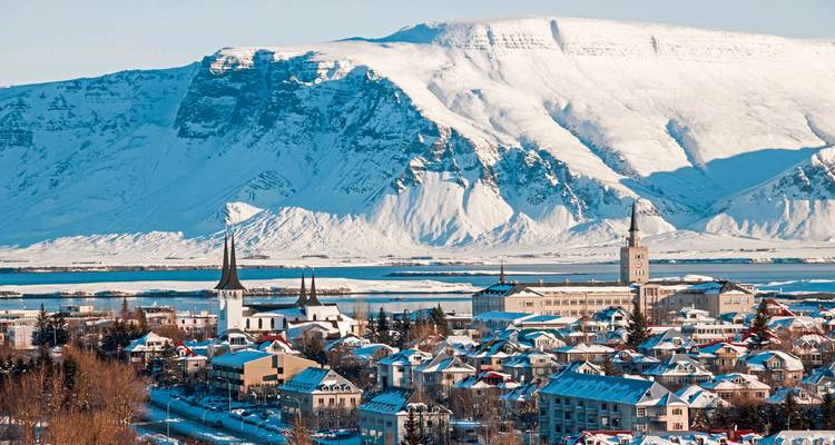 Stadtansicht mit verschneiten Bergen im Hintergrund.