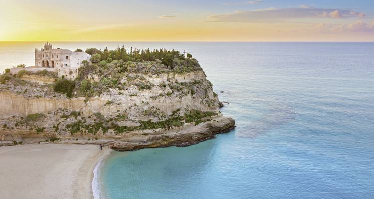 Vue panoramique d'une plage et du littoral au coucher du soleil.