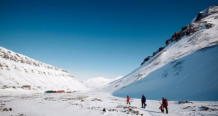 Menschen wandern durch ein schneebedecktes Tal.