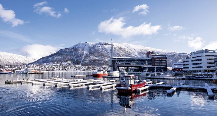 Hafenszene mit schneebedeckten Bergen und Gebäuden.