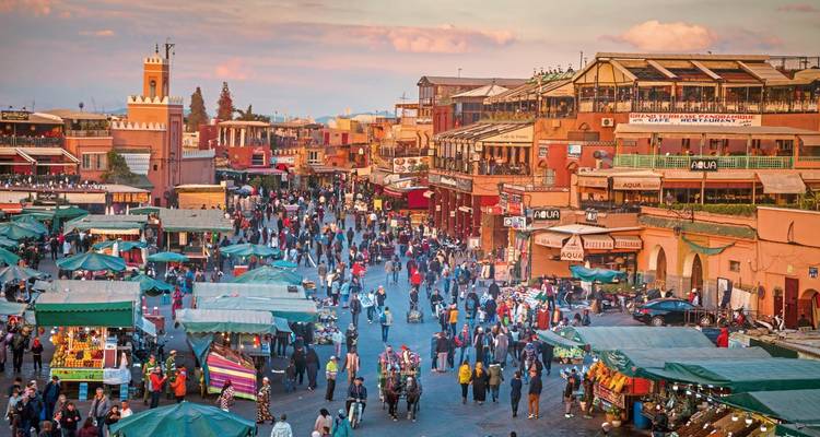 Crowded market square in Marrakesh with various stalls.