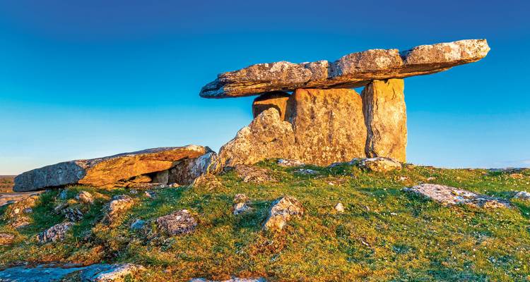 Alte Steinstruktur auf einem felsigen Hügel bei Sonnenuntergang.
