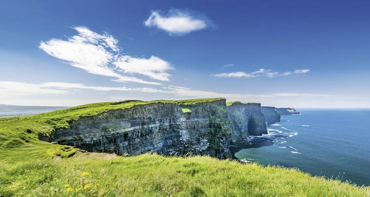 Klippen, die unter einem klaren blauen Himmel auf das Meer treffen.