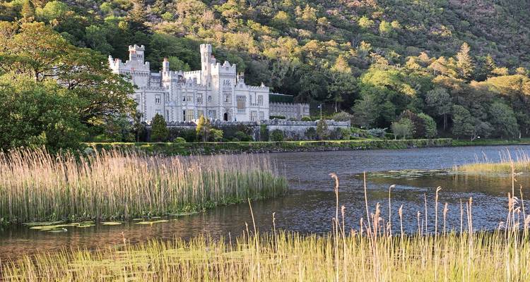 Kylemore Abbey by a tranquil lake with surrounding greenery.